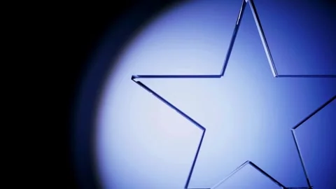 A crystal star trophy rotates under a blue spotlight Stock Footage 333810721