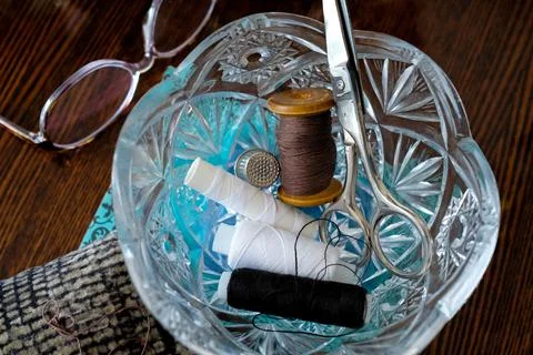 Crystal vase with spools of thread and scissors. Grandma's items Stock Photos