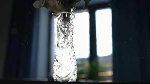 Crystal vase on table with dust flying around in sunbeam in slow motion. Close Video stock 221862906