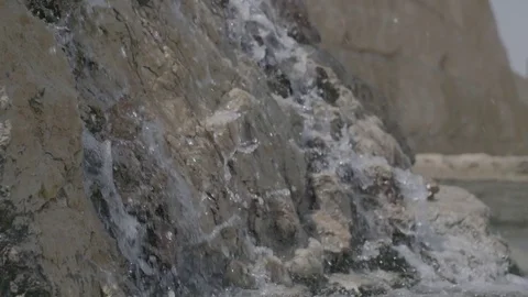 Crystal water splashes down over the side of a large rock Stock Footage 82833640