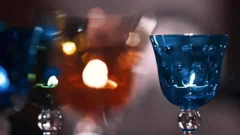 Crystal wine colored glasses moving in circle with candles inside. closeup Video stock 99996543