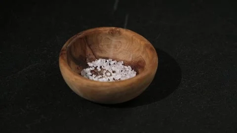 Crystals of table salt are poured into wooden bowl on a black background. Coarse Stock Footage 239278439