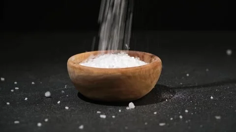 Crystals of table salt are poured into wooden bowl on a black background. Coarse Stock Footage 239278729