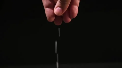 Crystals of table salt fall from the fingers of the hand on black background Stock Footage 239682628