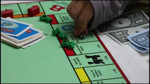 Cseup slow motion shot of a kid moving a piece across a Monopoly board Stock Footage 271048931