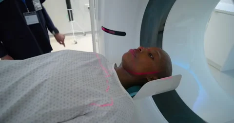 CT tech in hijab adjusting panel after red lasers while African American woman Stock Footage 343838032