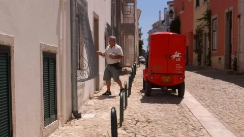 CTT mailman happily whistling while delivering mail to houses in Cascais Stock Footage 114436059