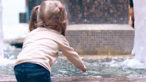 CU, Back view, Slow motion: Little sweet girl playing with water near fountain Stock Footage 105120942