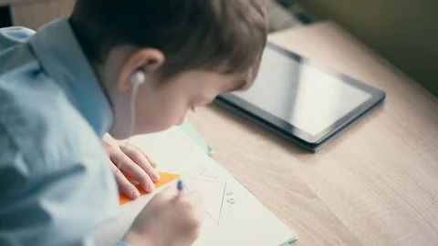 CU: Boy do school homework, writes ballpoint pen in notebook. In the ears are 스톡 동영상 105100069