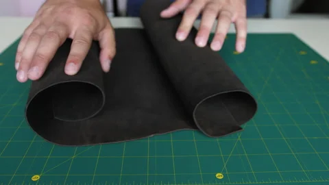 CU: Careful tailor cuts black leather cloth with special yellow box cutter Stock Footage 198496069