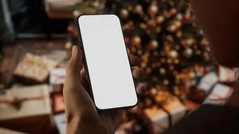 CU Caucasian man checking his phone near Christmas tree Stock Photos