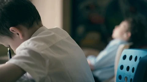 CU: Children do their homework, one sits at the table with notebooks Stock Footage 105099856