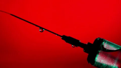 CU Clear liquid drips from needle of syringe Vaccine syringe red background 스톡 동영상 336587493