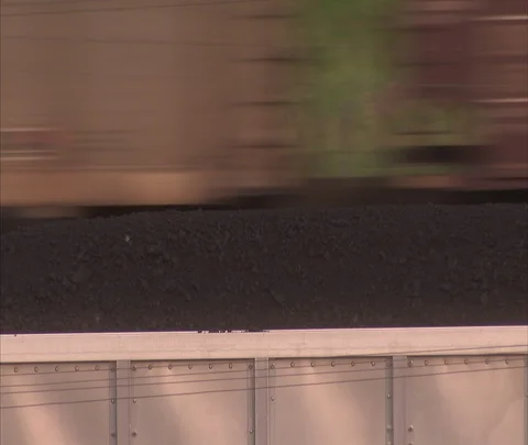 CU coal car with moving coal train passing in background, zoom out Stock Footage 86692503