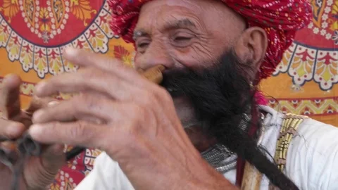 CU Hand-held Rajasthani elderly male starts to play the flute with his nose Stock Footage 69769251