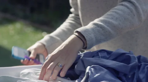 CU of lady hanging clothes washing on the line, using her iPhone Video stock 65438692