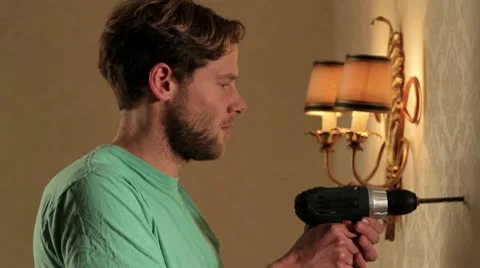 CU of a man drilling into a wall and hitting a pipe causing a leak Stock Footage 10703210