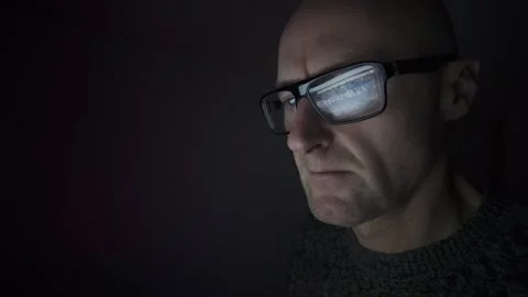 CU Man sat in dark room using a computer, refection in glasses. Stock Footage 327219906