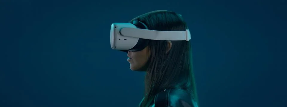 CU Portrait of Hispanic female using her VR metaverse headset against blue bg Stockfoto's