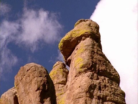CU of rock formations, with moving white clouds in blue sky. Stock Footage 86751221