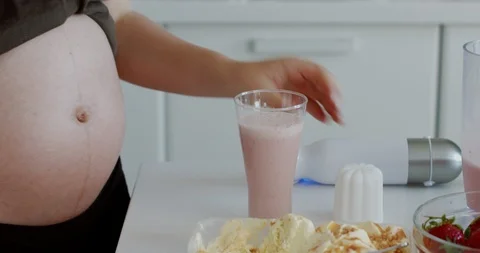 CU shot of milkshake while pregnant woman adding whipped cream to it Stock Footage 111539558