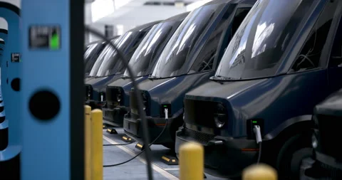 CU shot of modern electric EV delivery vans charging in company parking garage Stock Footage 238775022