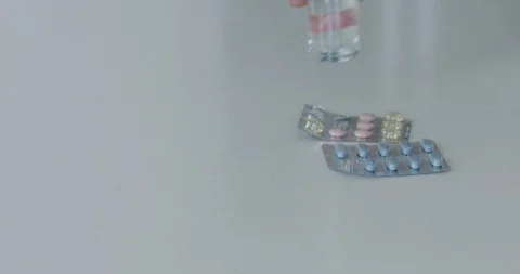 CU shot of pills laying on table and woman hand picking them up  Stock Footage 111539000