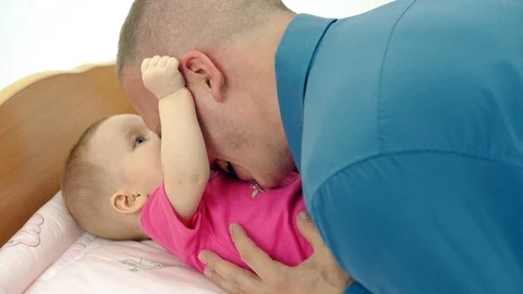 CU, Slow motion: Young father plays with little sweet daughter, who lies on a Stock Footage 105121358