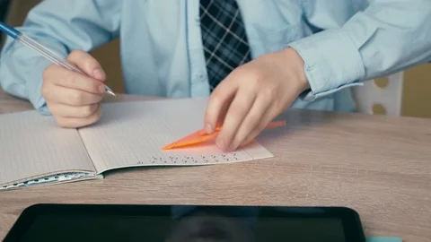 CU, Tracking: Schoolboy does homework, writes a pen in a notebook, uses a Stock Footage 105097402