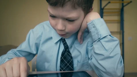 CU, Tracking. Slow motion: Pupil works on tablet computer, does lessons, flips Stock Footage 105099329