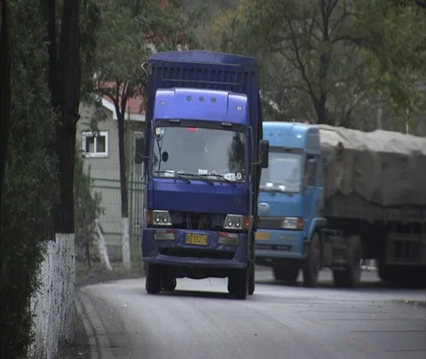 CU trucks carrying coal move through town Stock Footage 86744777