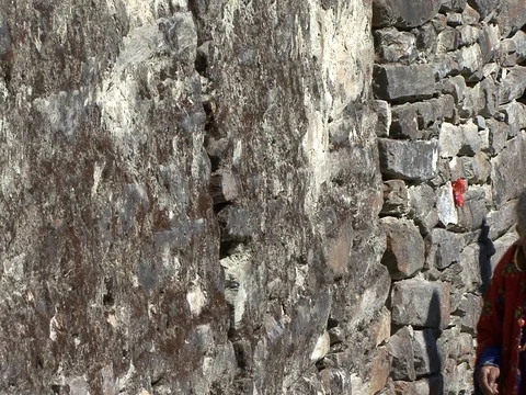 CU Villagers walking on mountain path past stone temple. Stock Footage 86748865