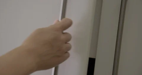 CU woman's hand opens and closes white cupboard door 4K Stock Footage 90957071