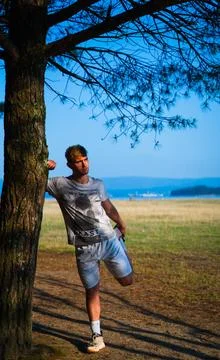 Cuadriceps stretch leaning on a tree Stock Photos