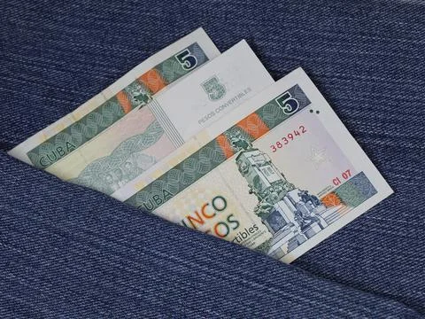 Cuban banknotes of five pesos between blue denim fabric Stock Photos