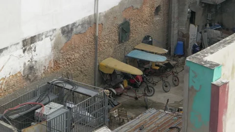 Cuban cycle rickshaws parked in a small backyard in a poor urban area of Havana Stock Footage 225711548