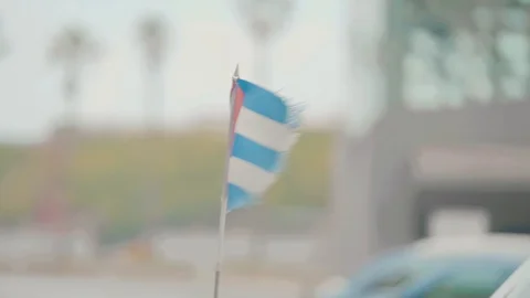 Cuban flag flapping in the wind on front of a vintage cuban car Stock Footage 88763454