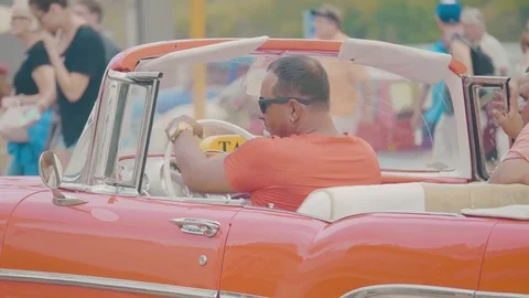 Cuban man driving a red open top classic car in city of havana Stock Footage 88763384