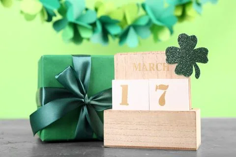 Cube calendar with date of St. Patrick's Day and gift box on green grunge tab Stock Photos
