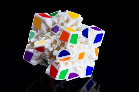 This is a cube with colored faces puzzle on a dark background with reflection. A Stock Photos