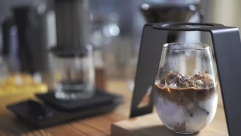 Cube of ice add on glass of latte coffee, home brewing process Stock Footage 178398487