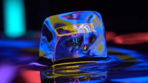 Cube of ice rotating in water with yellow neon lighting Stock Footage 106829616