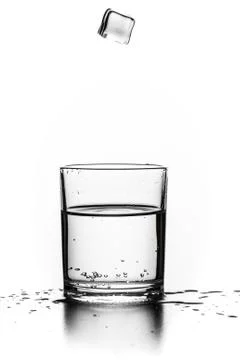 Cube of ice thrown into a glass with liquid Stock Photos