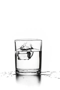 Cube of ice thrown into a glass with liquid Stock Photos