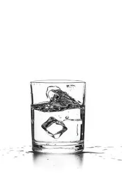 Cube of ice thrown into a glass with liquid Stock Photos