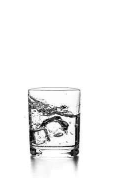 Cube of ice thrown into a glass with liquid Stock Photos