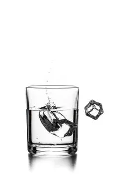 Cube of ice thrown into a glass with liquid Stock Photos
