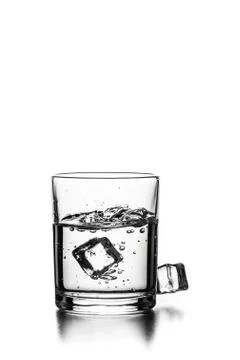 Cube of ice thrown into a glass with liquid Stock Photos