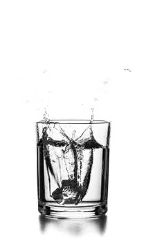 Cube of ice thrown into a glass with liquid Stock Photos