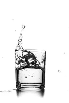 Cube of ice thrown into a glass with liquid Stock Photos
